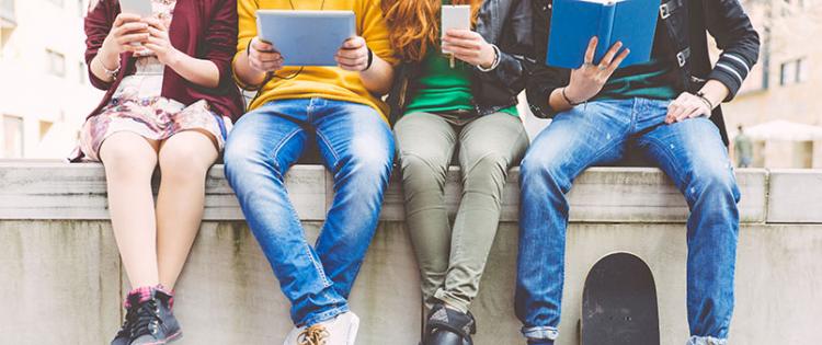 legs of four teens in a row sitting on a ledge