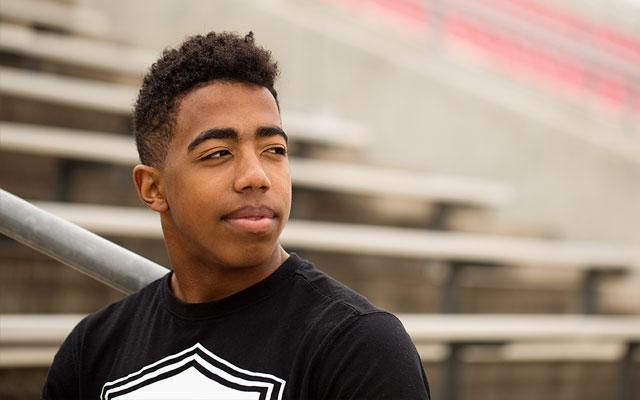 young man standing in front of bleachers looking into distance